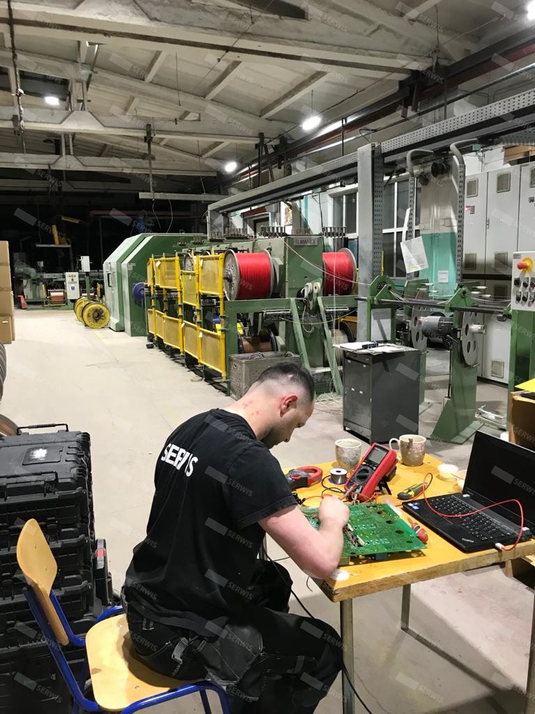 Technik serwisowy naprawiający płytę elektroniczną w zakładzie przemysłowym