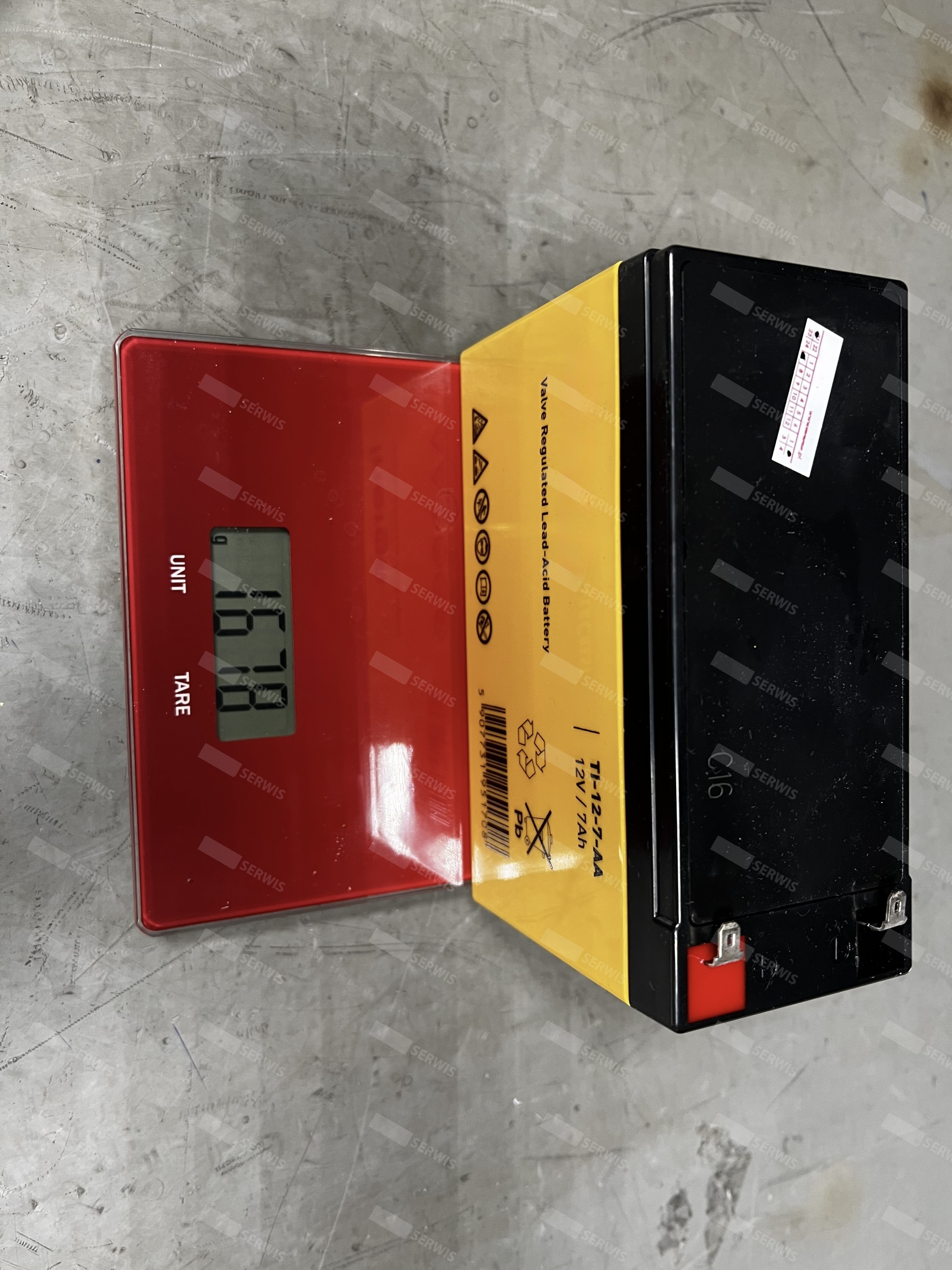Akumulator UPS Inerge ważony na elektronicznej wadze, wskazujący wagę 1.570 kg.