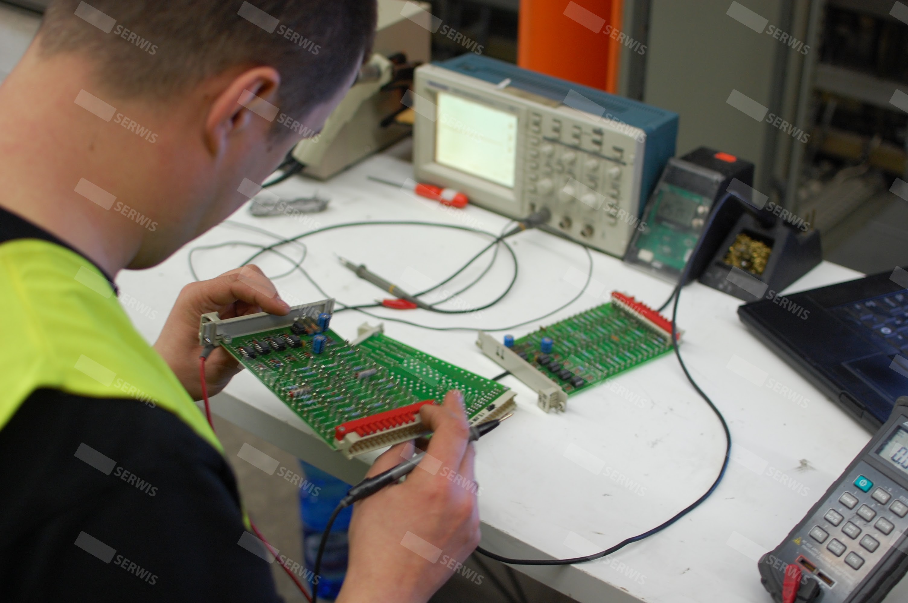 Technik serwisowy testujący płytę drukowaną za pomocą oscyloskopu