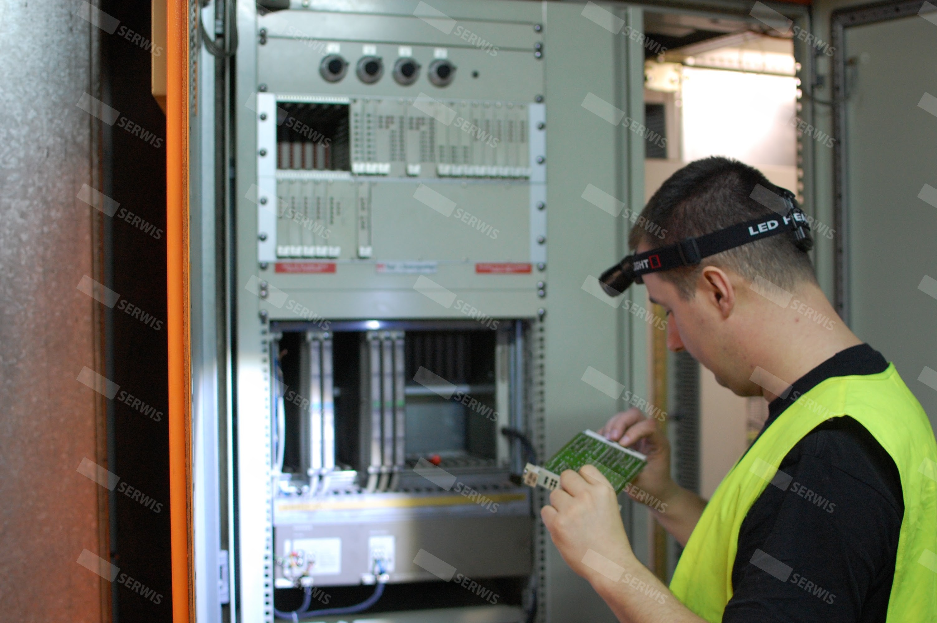 Technik serwisowy sprawdzający układ elektroniczny w szafie sterowniczej