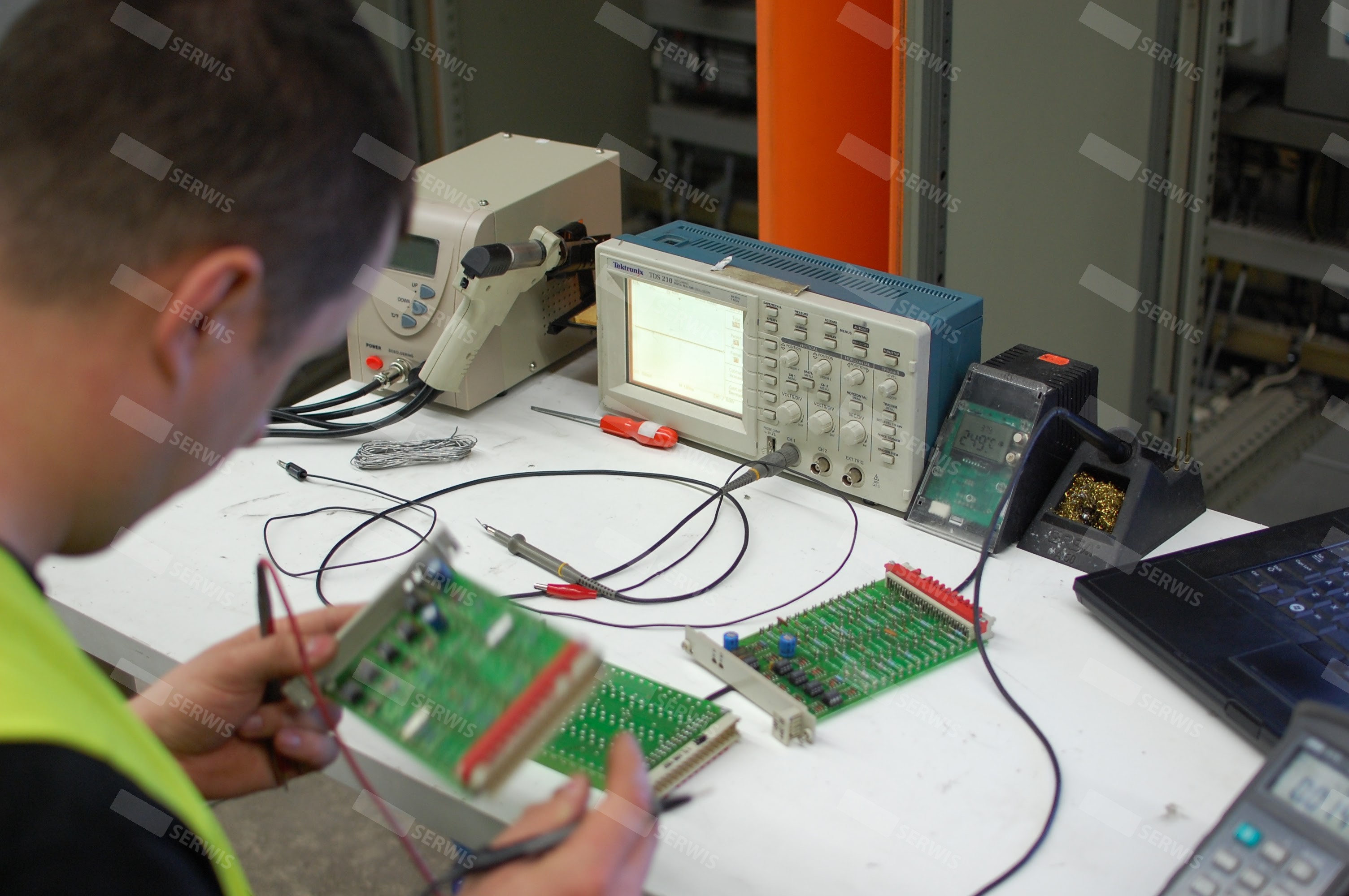 Technik serwisowy testujący płytę elektroniczną przy użyciu oscyloskopu