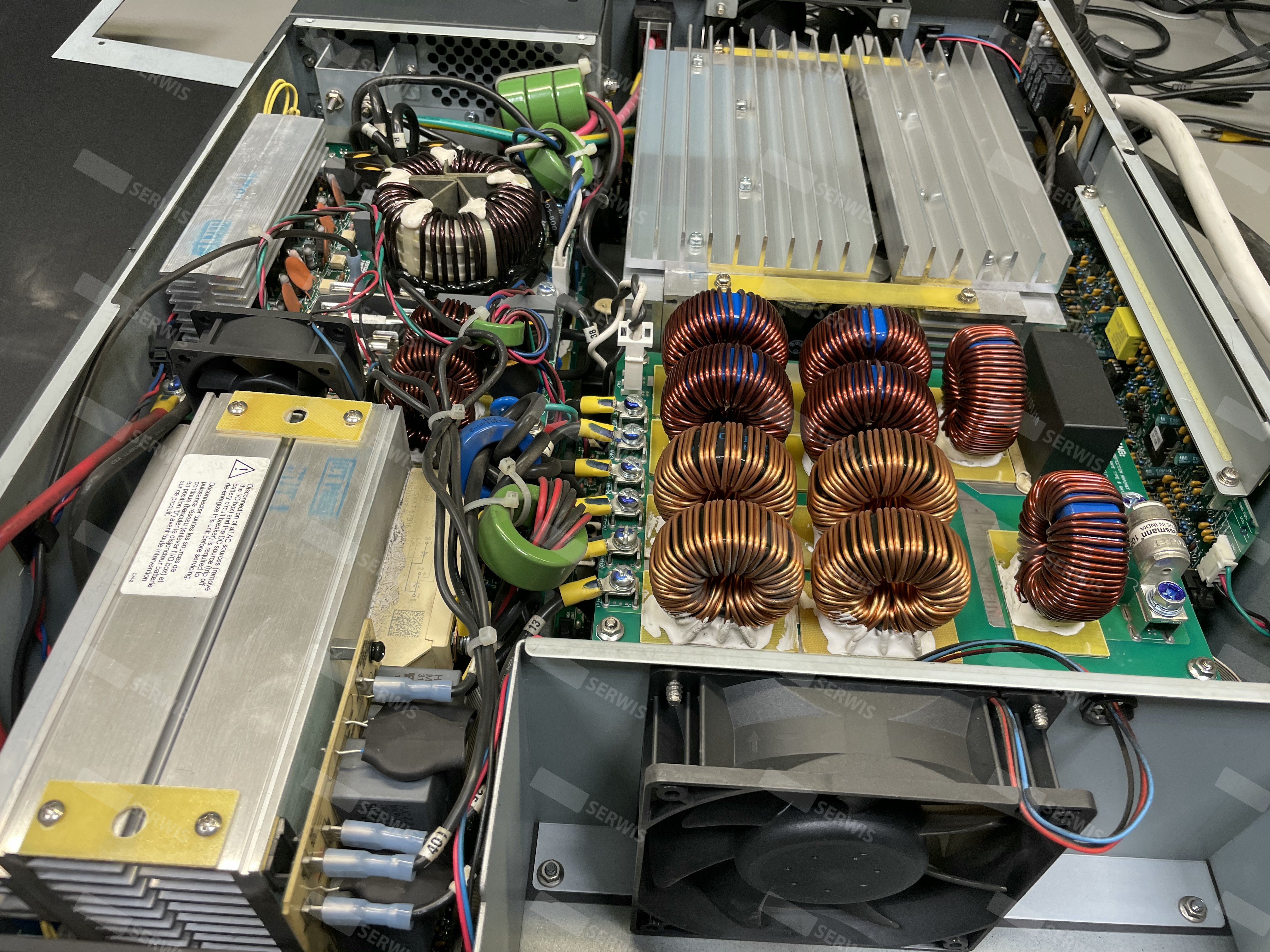 Wnętrze urządzenia elektronicznego z widocznymi cewkami indukcyjnymi i układem chłodzenia