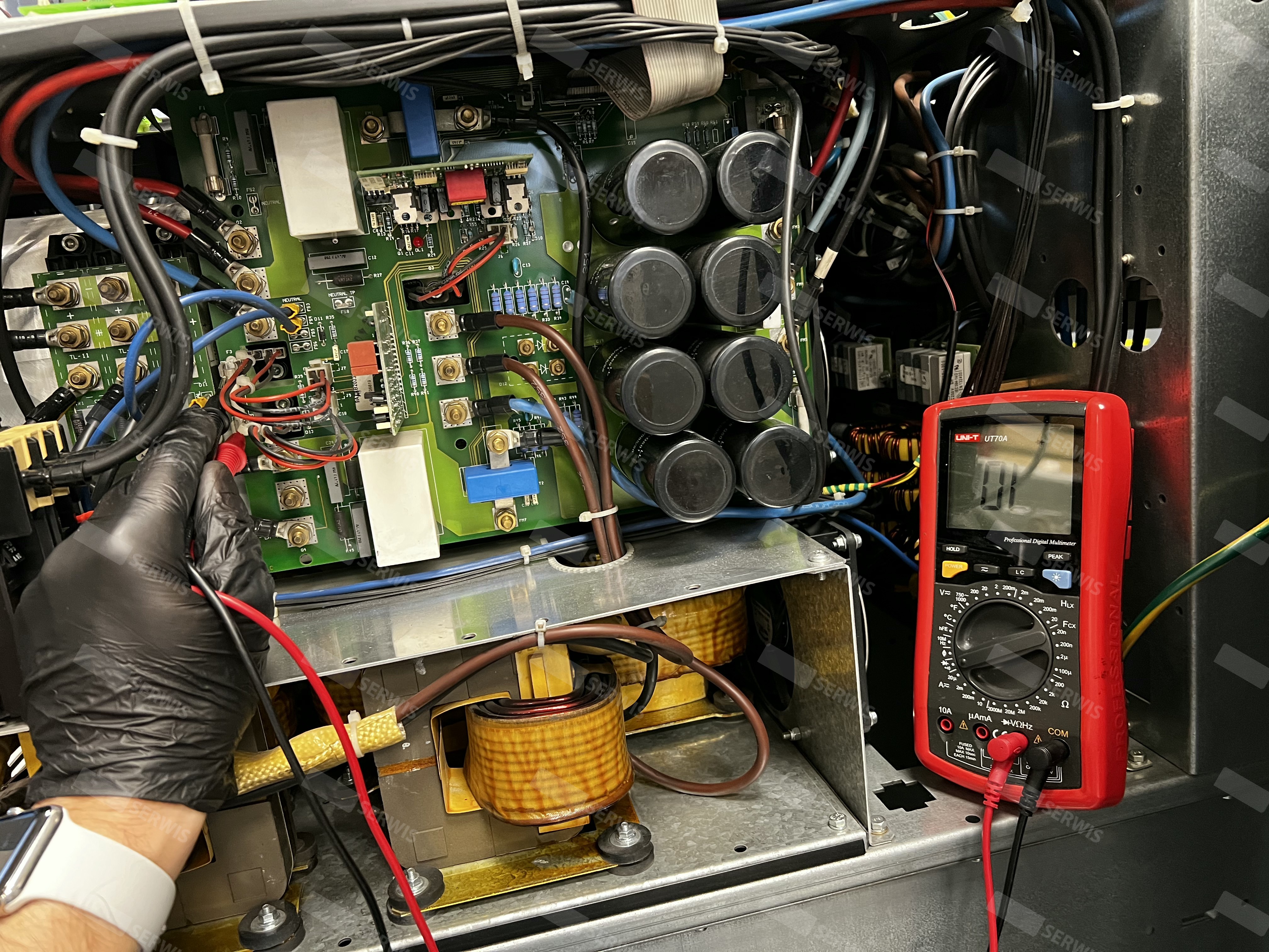 Technik sprawdzający napięcie w dużym UPS za pomocą multimetru