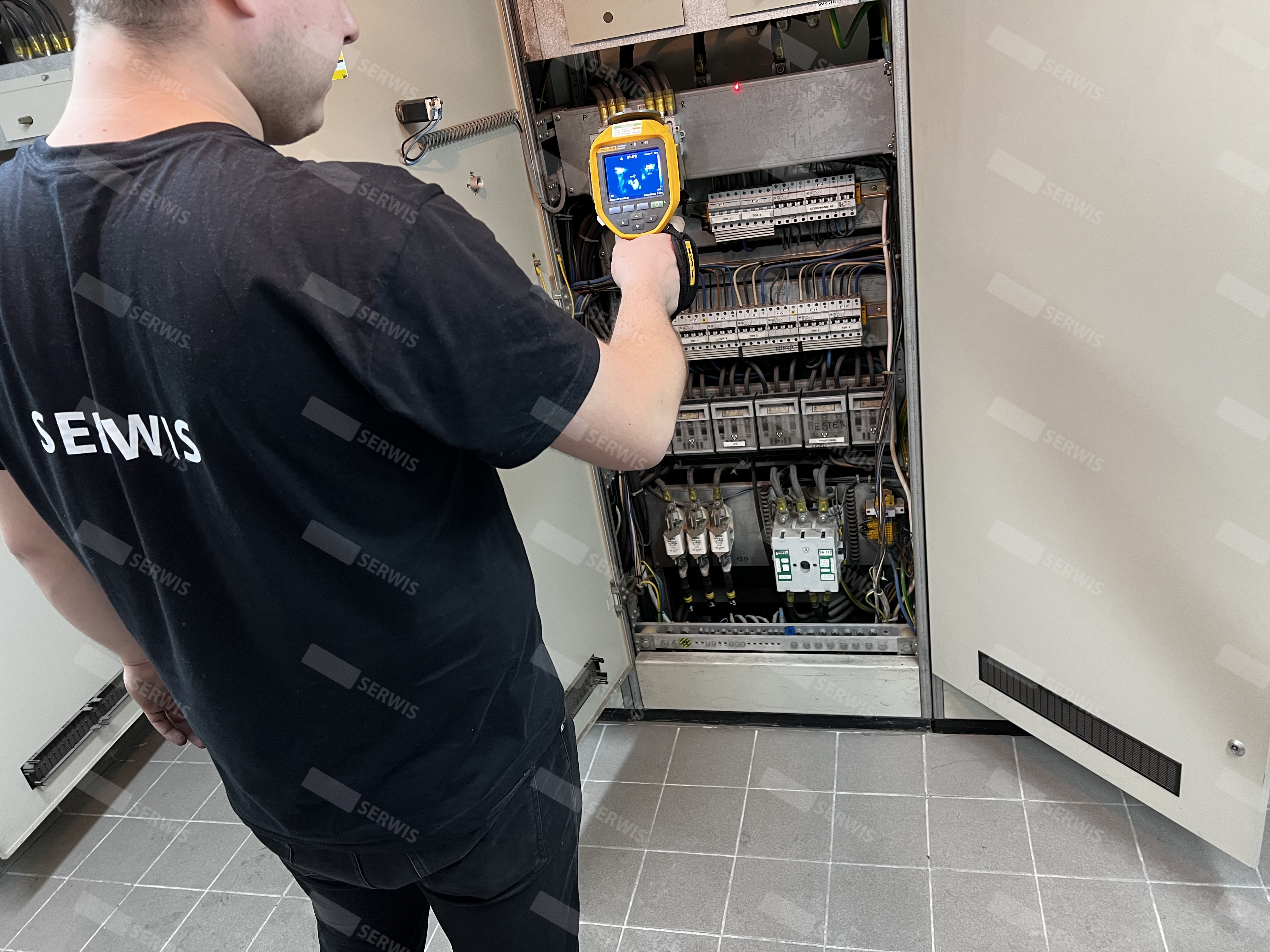 Technik przeprowadzający przegląd termowizyjny szafy elektrycznej w serwisie UPS