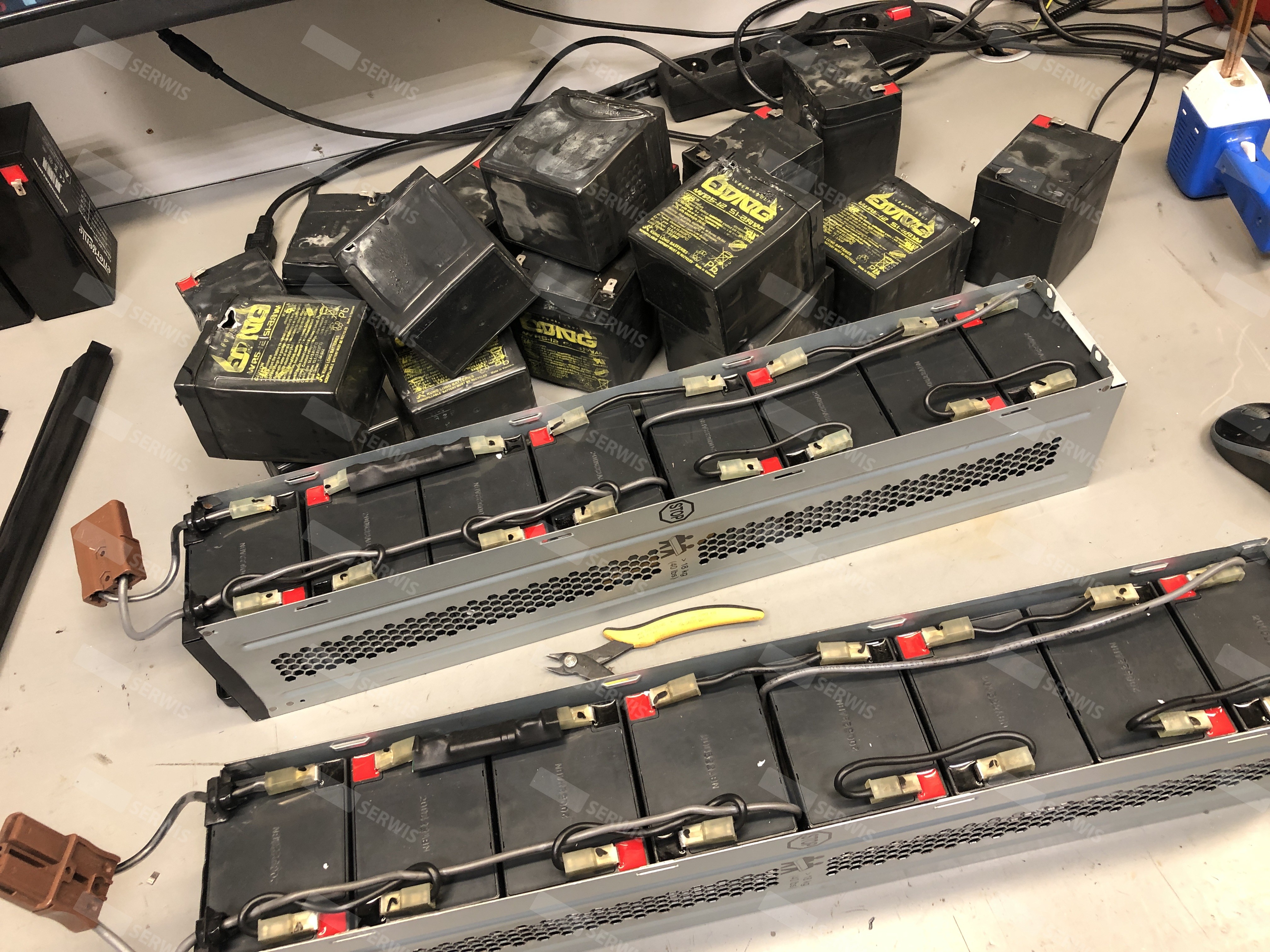 Stos akumulatorów UPS na biurku w serwisie, przygotowanie do wymiany