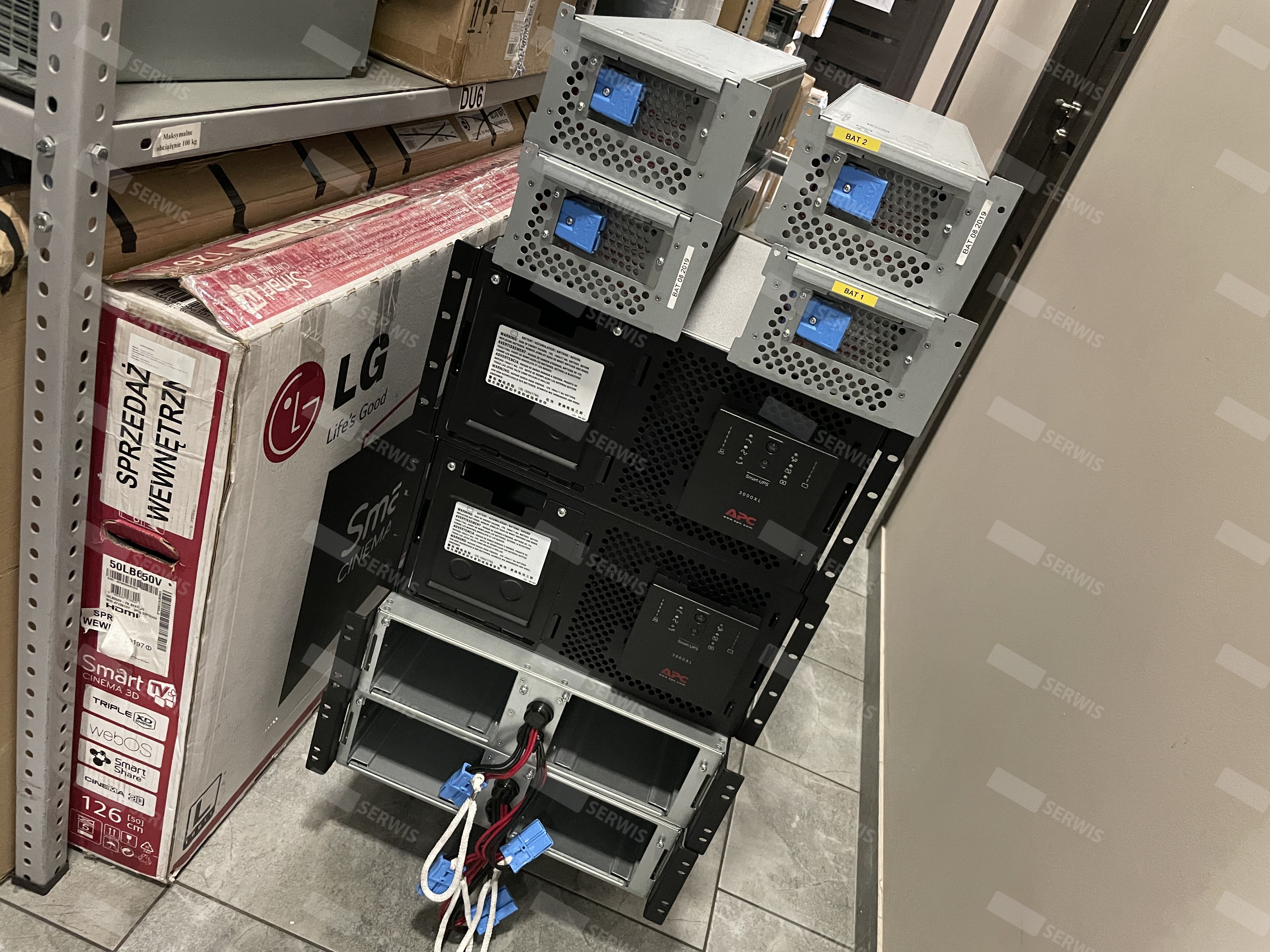 Stosy zasilaczy UPS w magazynie, przygotowane do przeglądu serwisowego