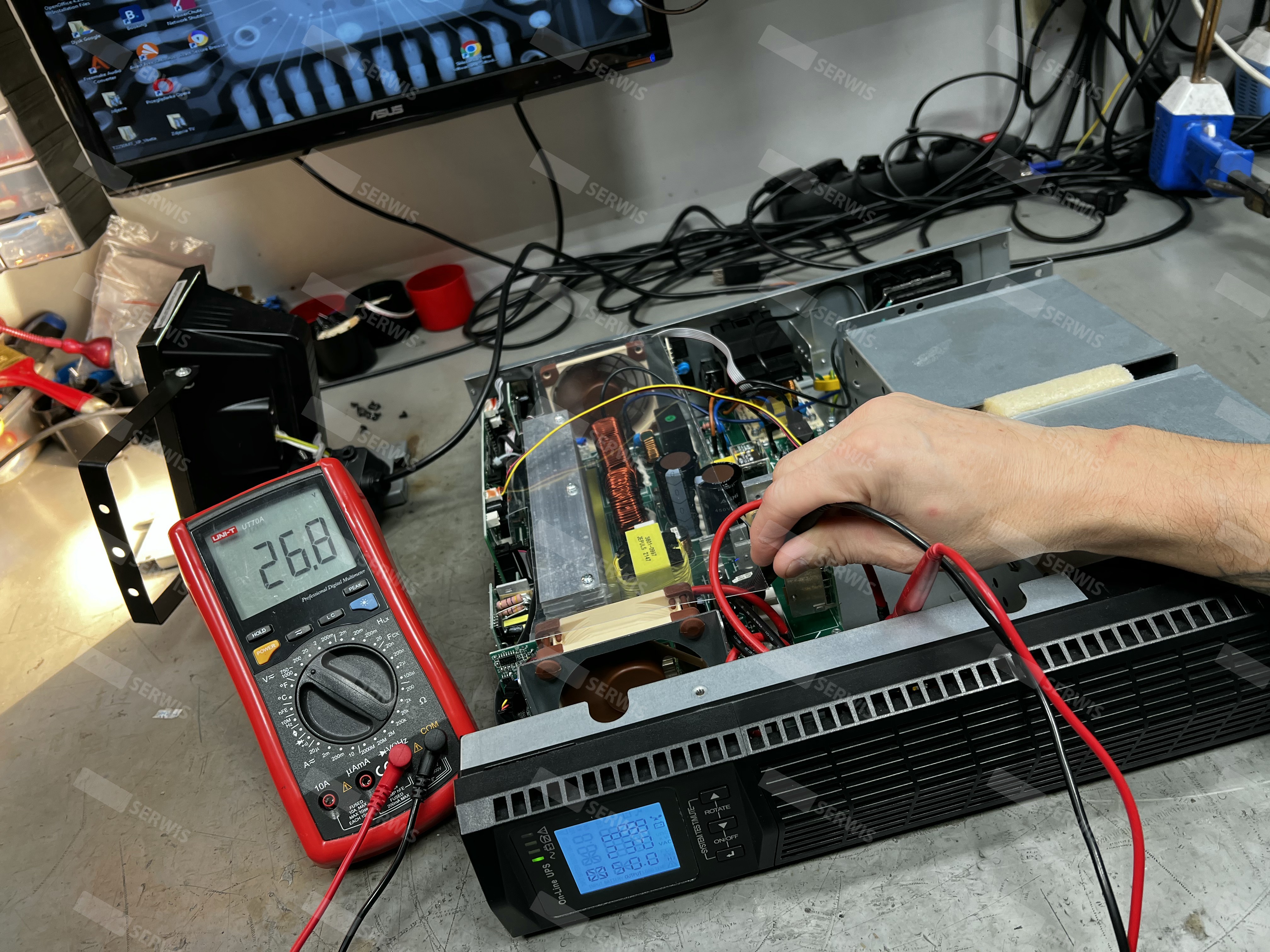 Technik mierzący napięcie w zasilaczu UPS za pomocą multimetru
