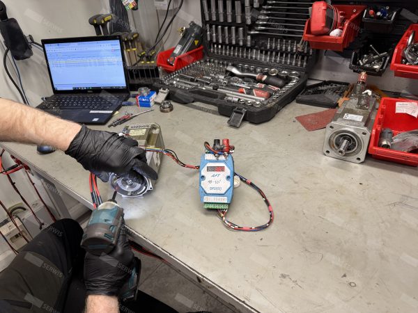 Technik testujący silnik elektryczny na stanowisku serwisowym z narzędziami