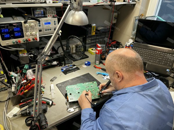 Technik serwisowy naprawiający płytę główną komputera przemysłowego na stanowisku pracy