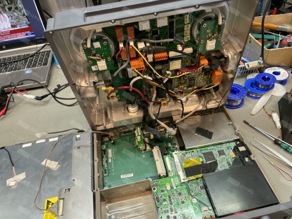 Otwarte wnętrze panelu operatorskiego z widocznymi komponentami elektronicznymi na stole serwisowym